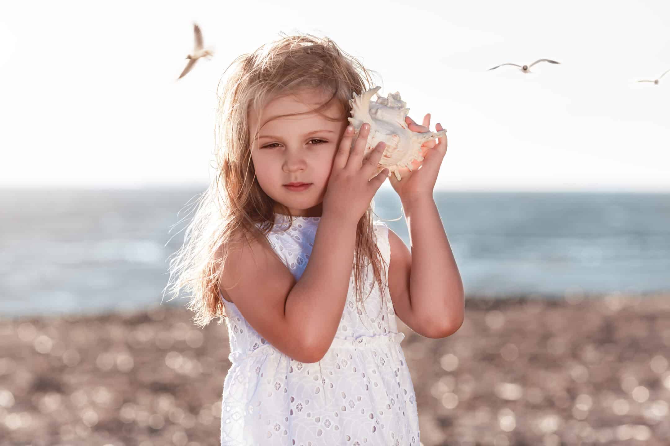jeune fille qui écoute la mer à travers un coquillage